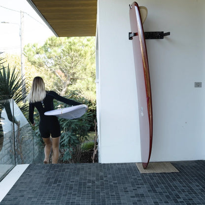 Rack de surf vertical EDERRAK en plastique recyclé avec un longboard rangé debout contre le mur